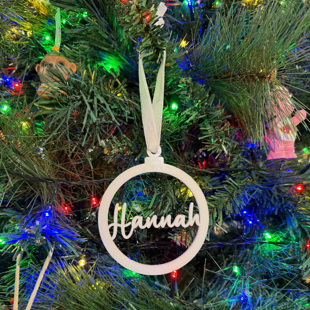 Decorative ornament with 'Hannah' on a Christmas tree with lights and ornaments.