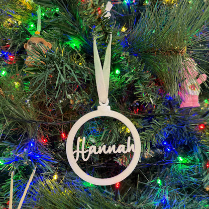 Decorative ornament with 'Hannah' on a Christmas tree with lights and ornaments.