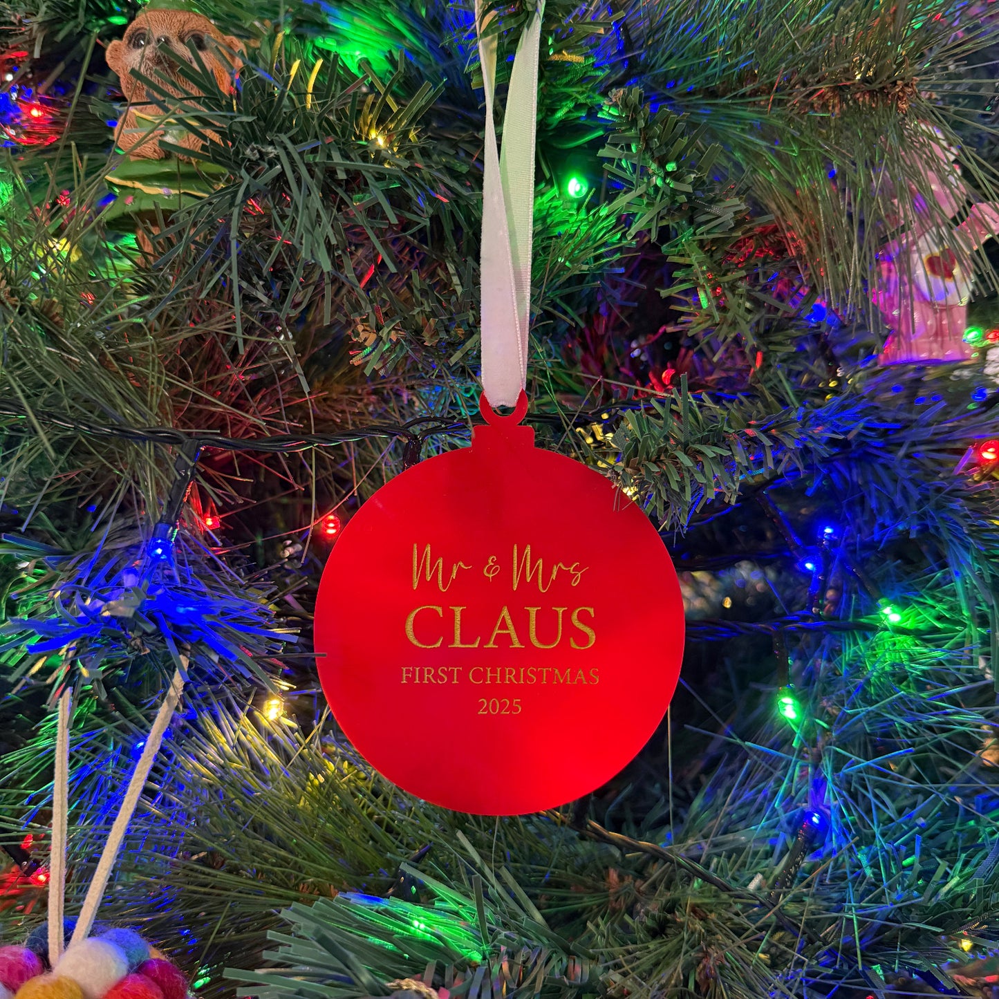 Red ornament with 'Mr. & Mrs. Claus' text on a Christmas tree.